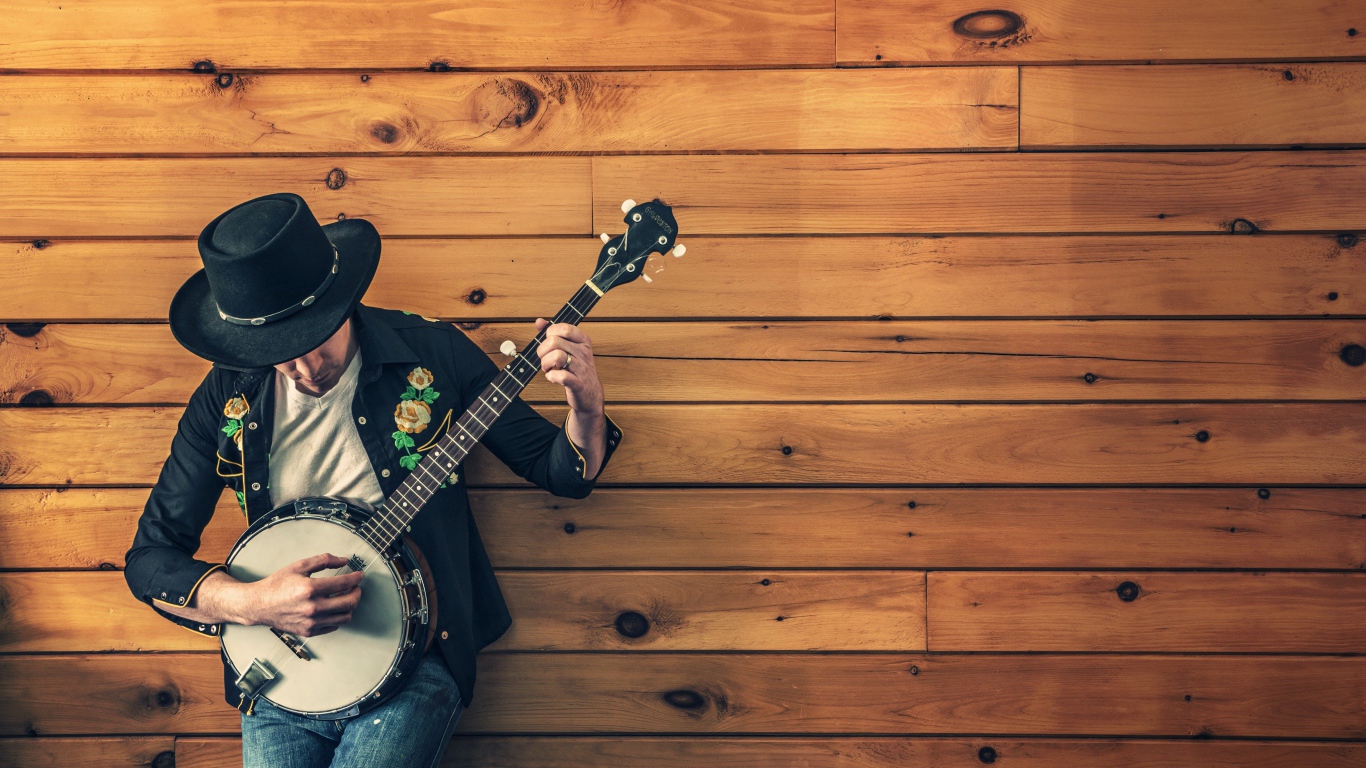 Musician guy plays banjo against a wooden wall
