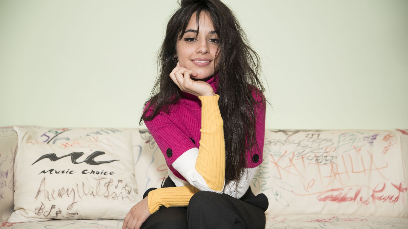 Улыбающаяся Камила Кабельо сидит на диване