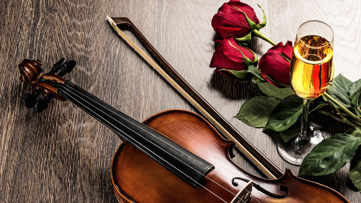 Скрипка лежит на столе с бокалом шампанского и красными розами