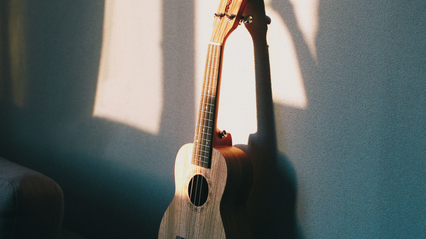 Желтая гитара стоит у серой стены