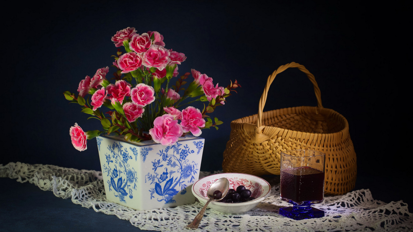 Букет гвоздик в красивой вазе на столе с корзиной и соком