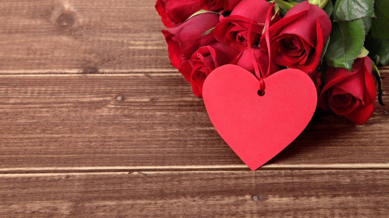 Букет красных роз на деревянном столе с красным сердцем