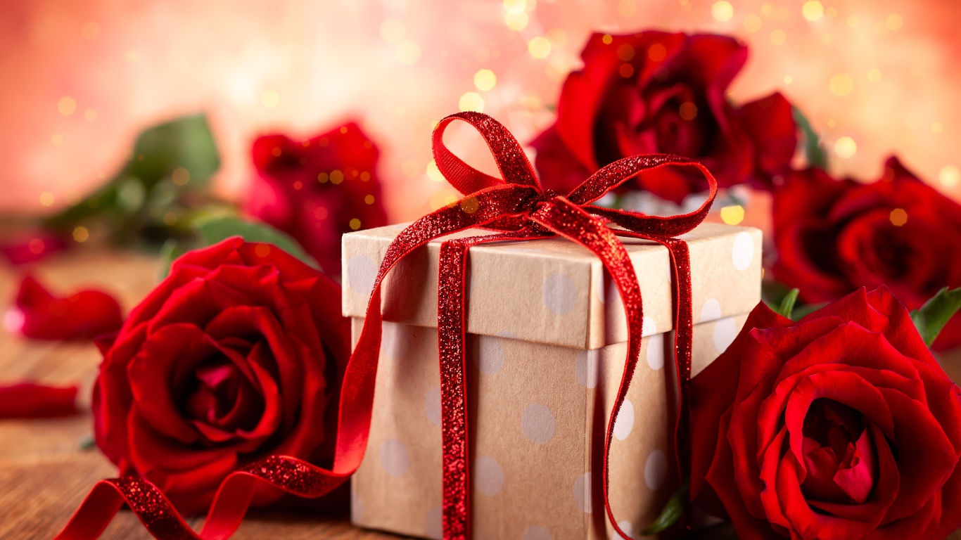 Подарок с красным бантом на столе с букетом роз