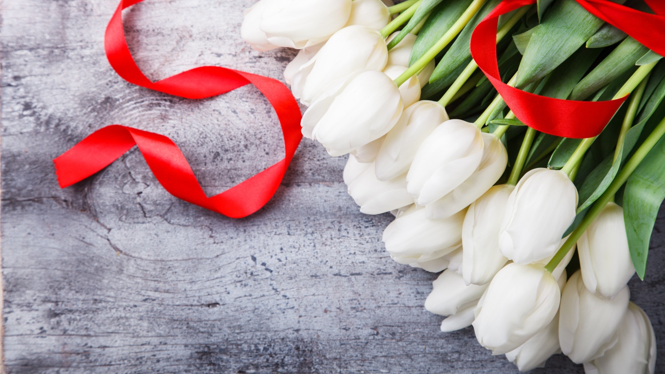 Букет белых тюльпанов с красным бантом на сером столе