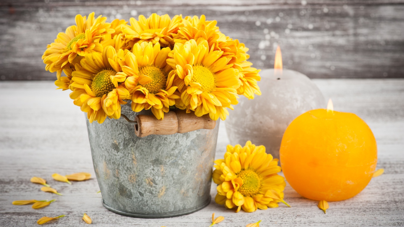 Букет желтых хризантем в ведерке на столе со свечами
