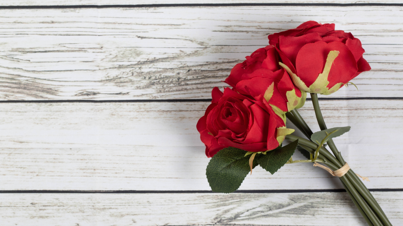 Три искусственные красные розы на деревянном фоне