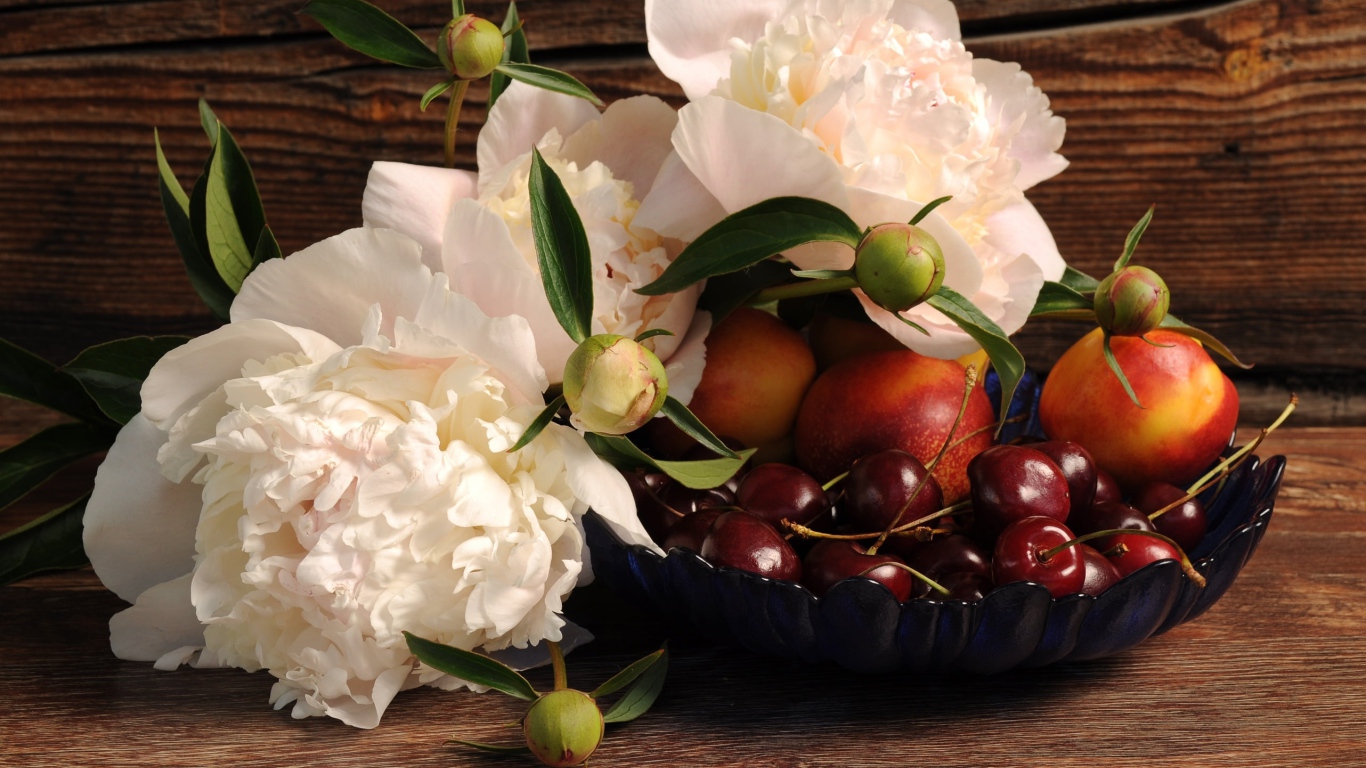Три красивых белых пиона на столе с вазой с черешней и нектарином