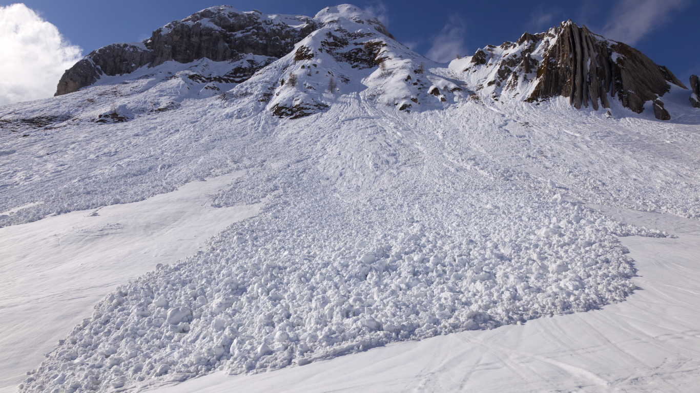 Белая лавина сходит с гор солнечным днем