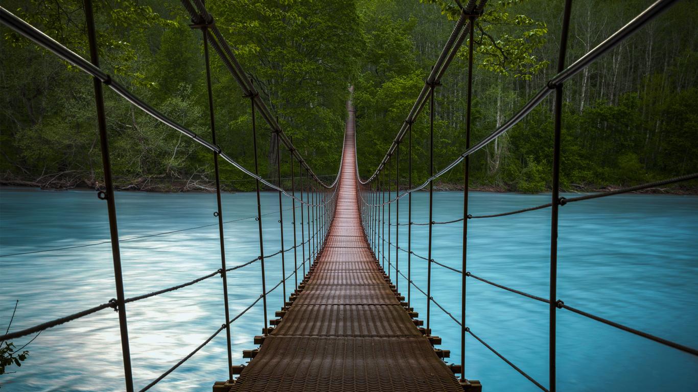 Подвесной мост над быстрой рекой с голубой водой