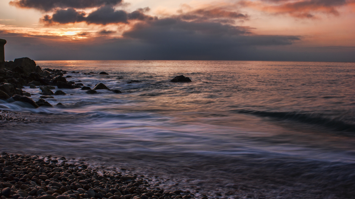 Мелкие камни на берегу моря на закате