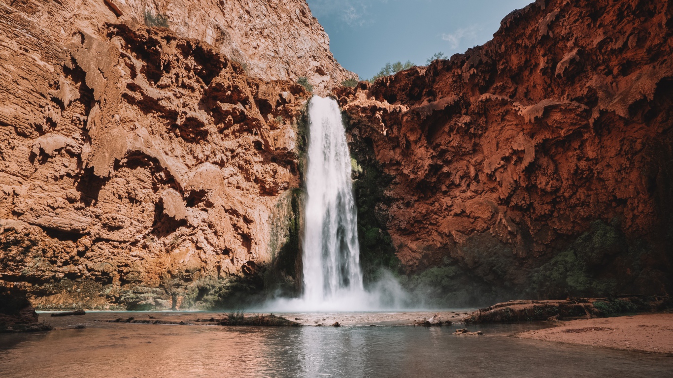 Водопад стекает со скалы в озеро 