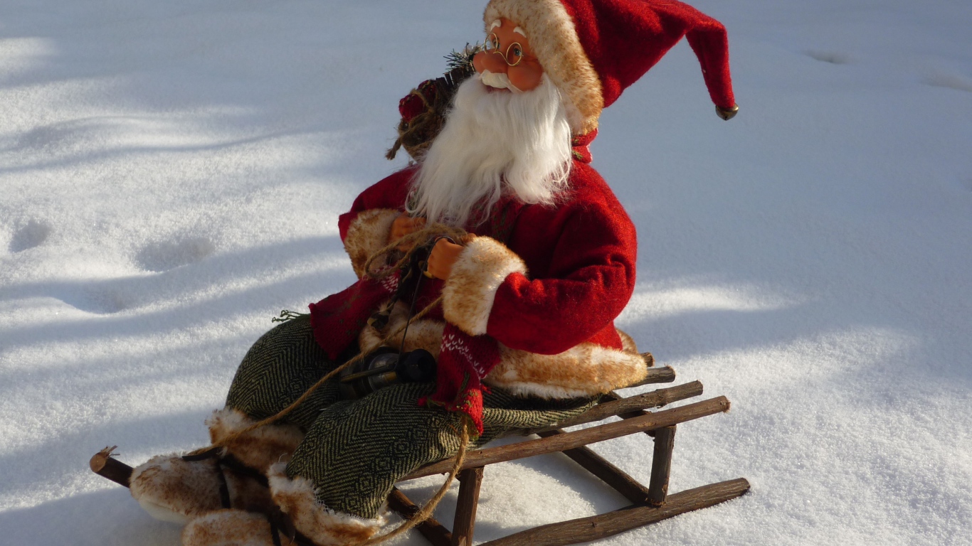Игрушка деда Мороза на санках стоит на снегу