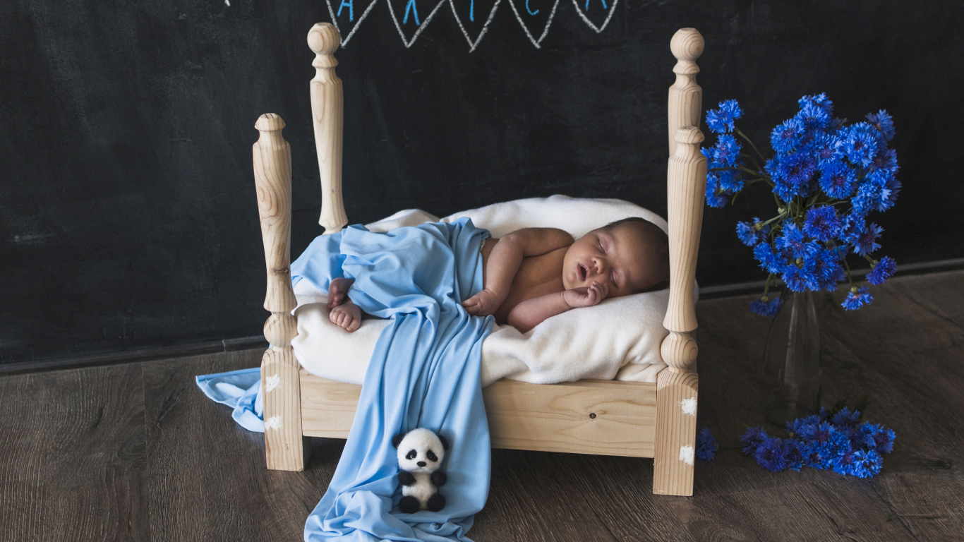 Грудной ребенок спит на деревянной кровати