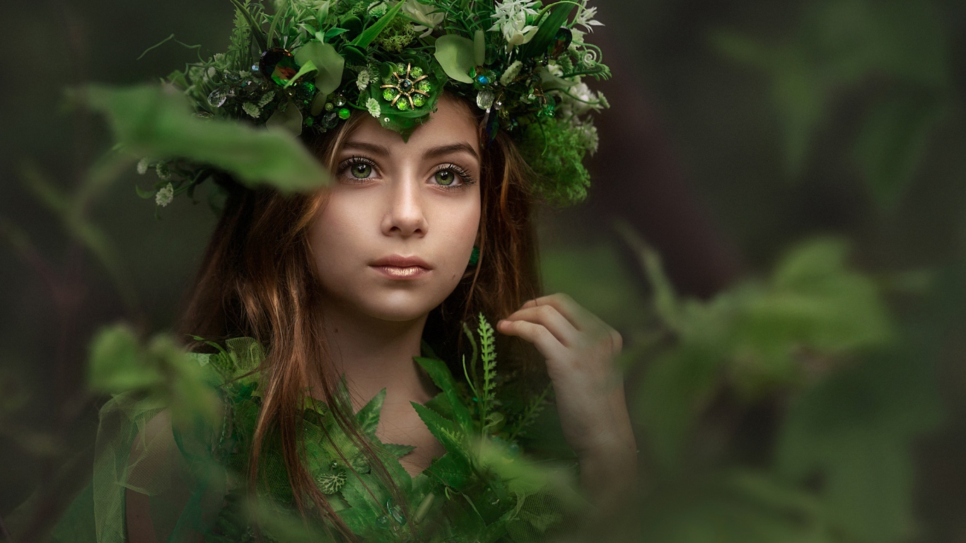 Красивая голубоглазая девочка с венком на голове у дерева