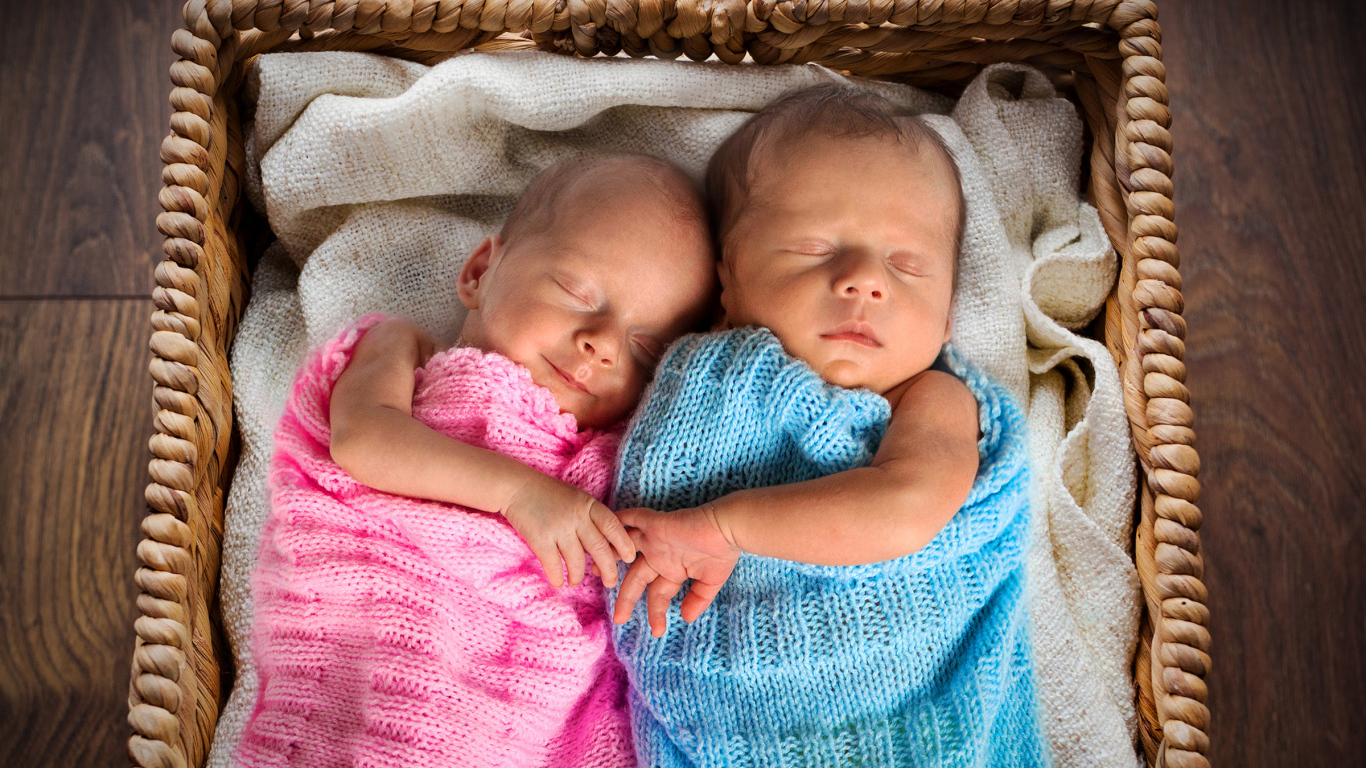 Грудные мальчик и девочка спят в плетеной корзине