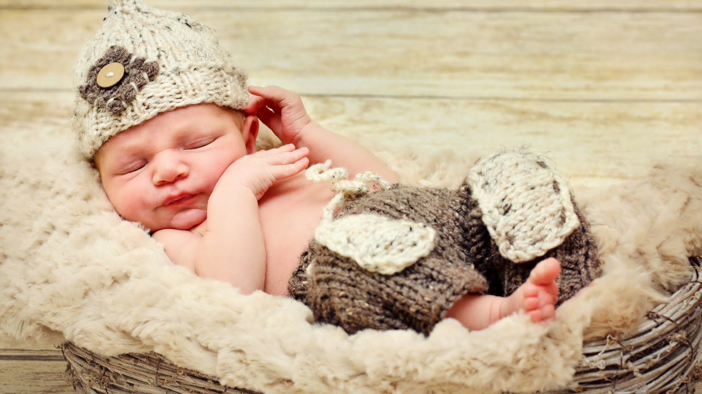 Маленький мальчик в вязаной шапке спит в корзине