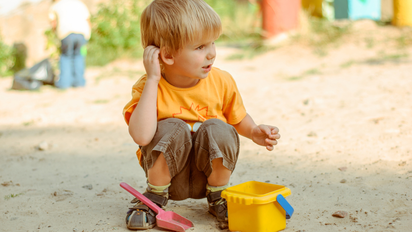 Маленький мальчик играет на песке 