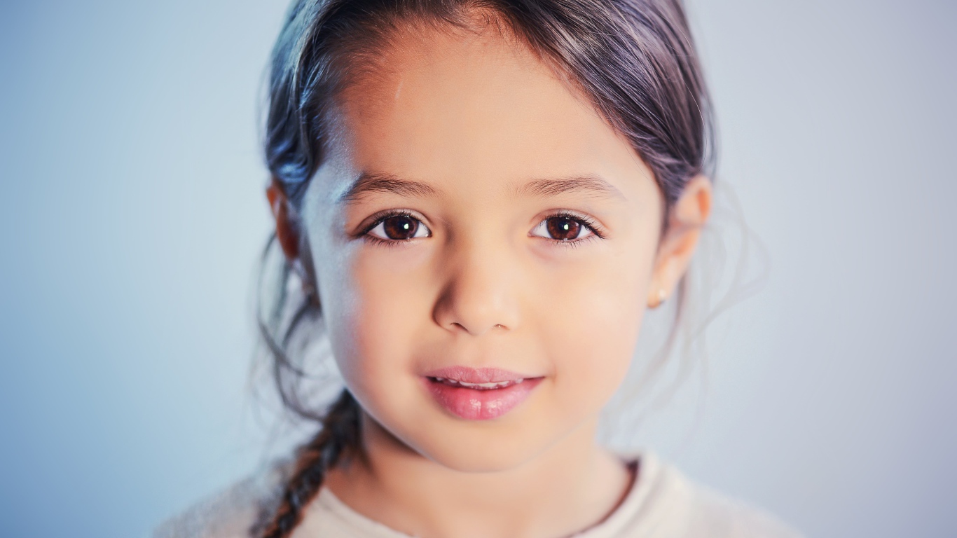 Маленькая кареглазая девочка на сером фоне