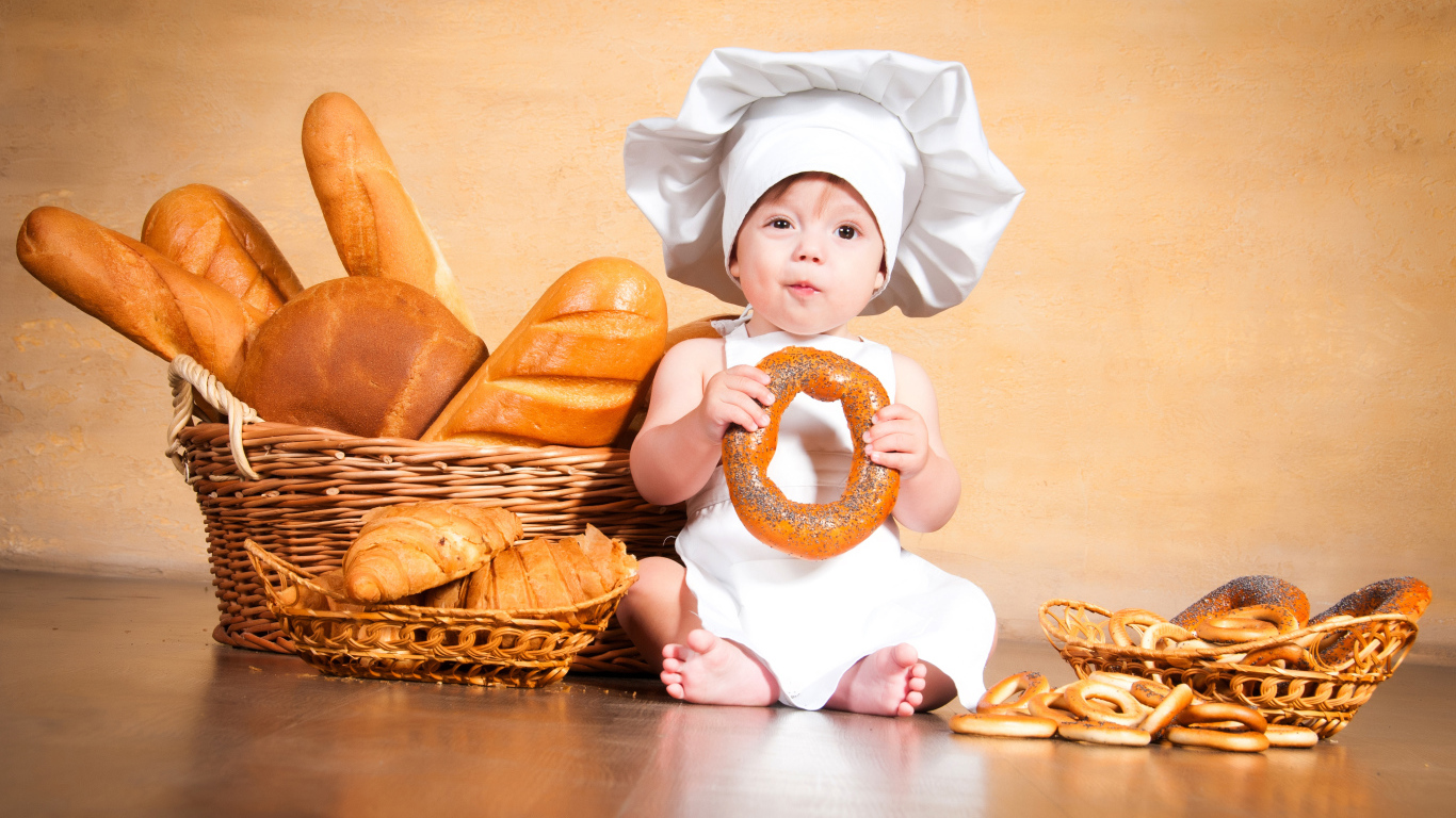 Маленький поваренок на столе со свежей выпечкой