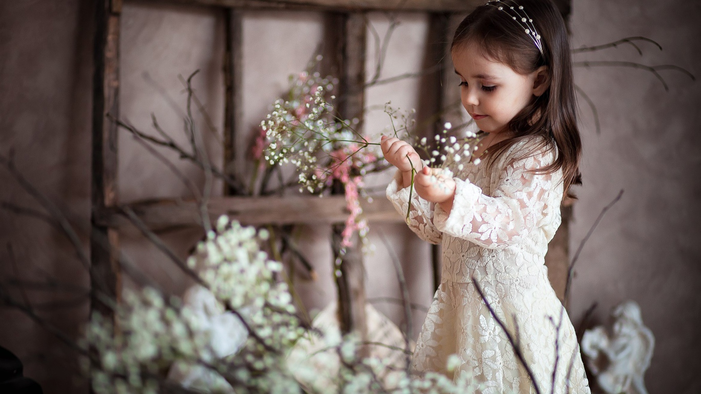 Маленькая девочка в красивом платье с белыми цветами в руке