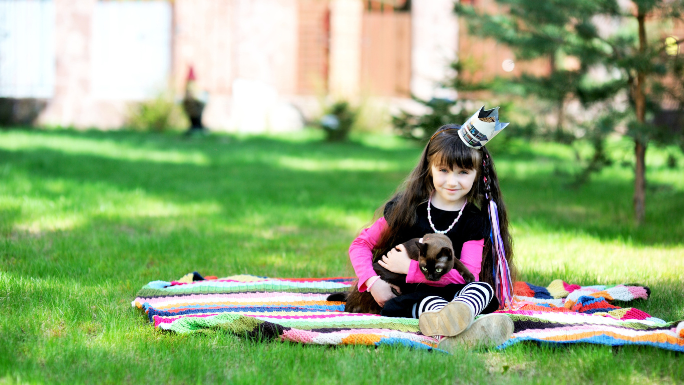 Маленькая девочка с котом сидит на зеленой траве