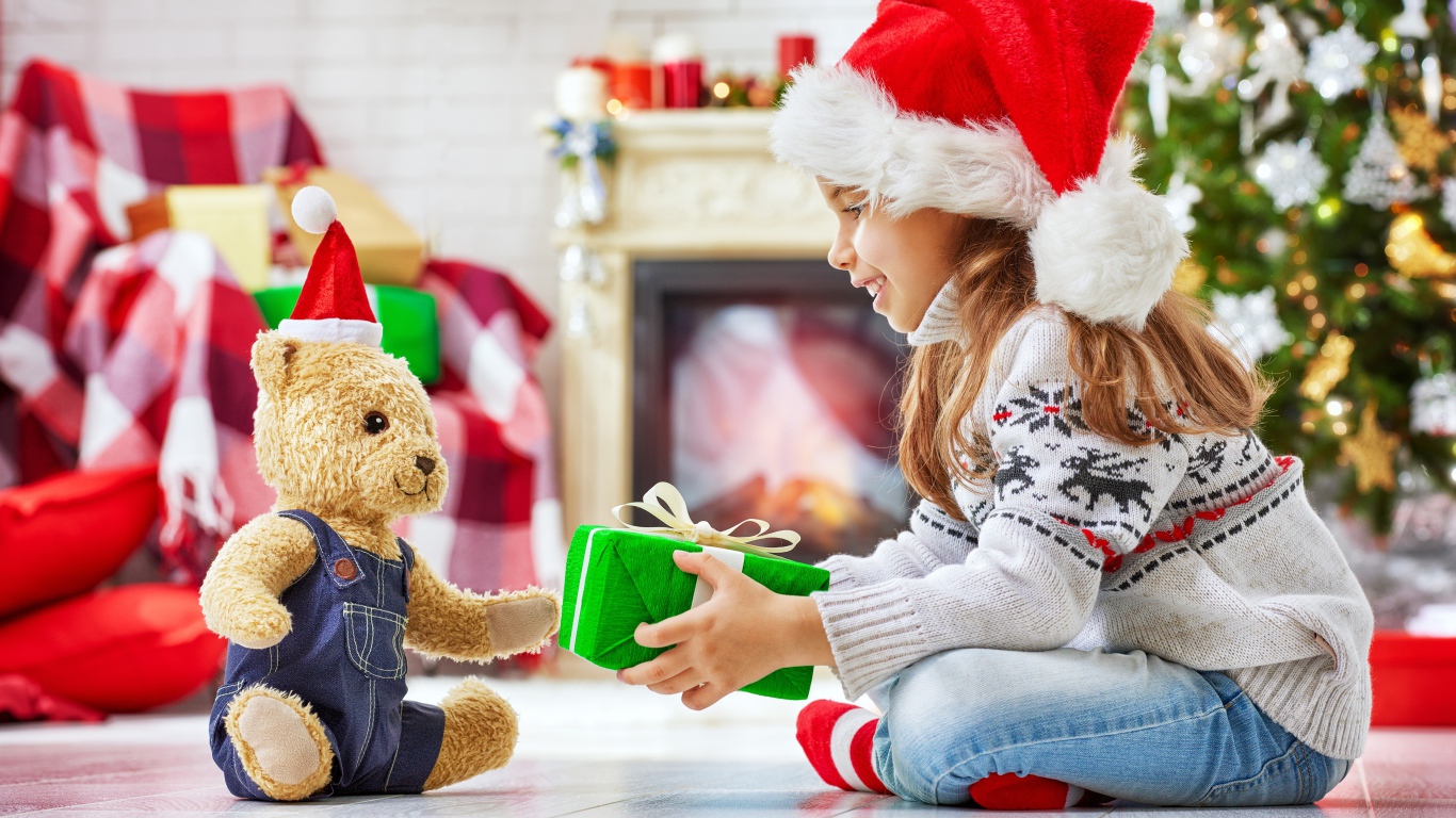 Маленькая девочка с медвежонком Тедди у елки с подарками на Новый год