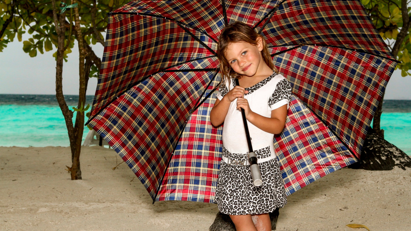 Маленькая девочка с большим зонтом на пляже