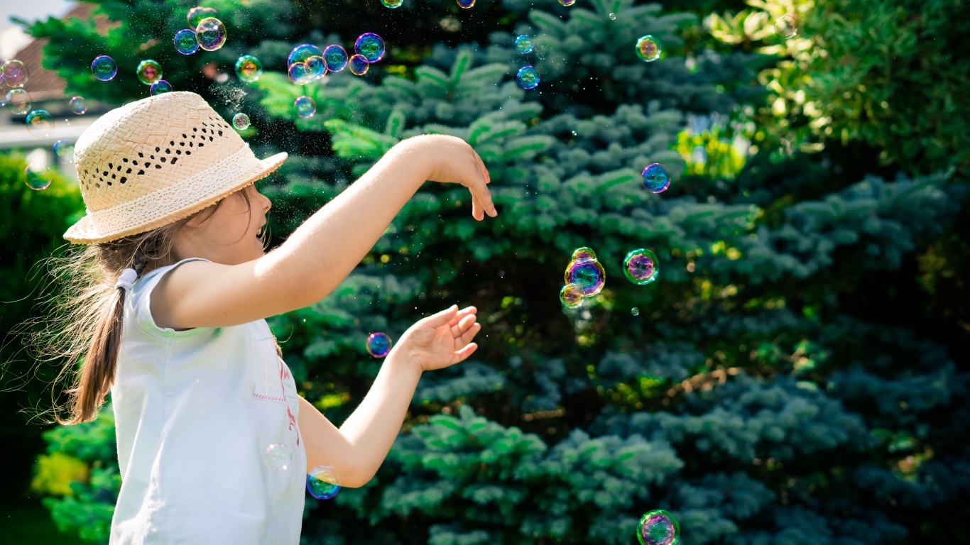 Маленькая девочка с мыльными пузырями у елки