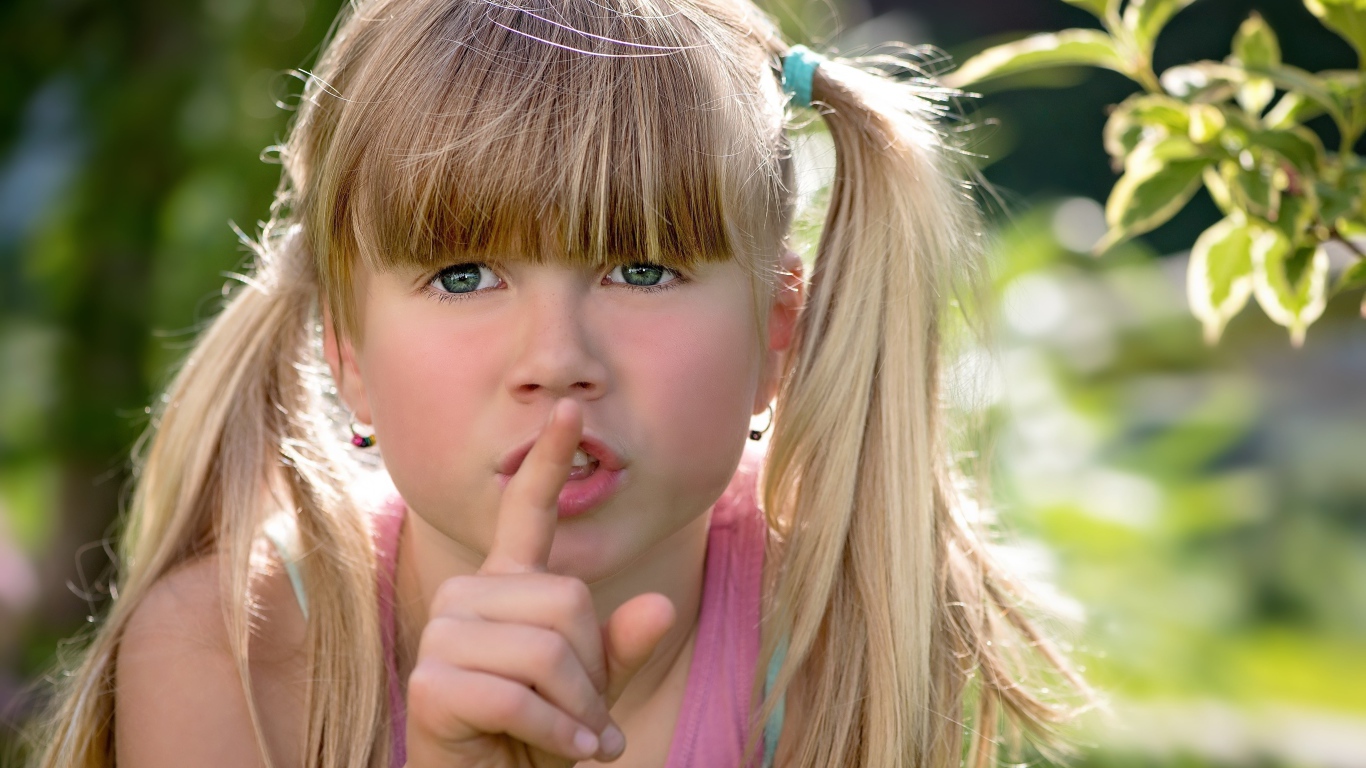 Маленькая зеленоглазая девочка с пальцем у рта 