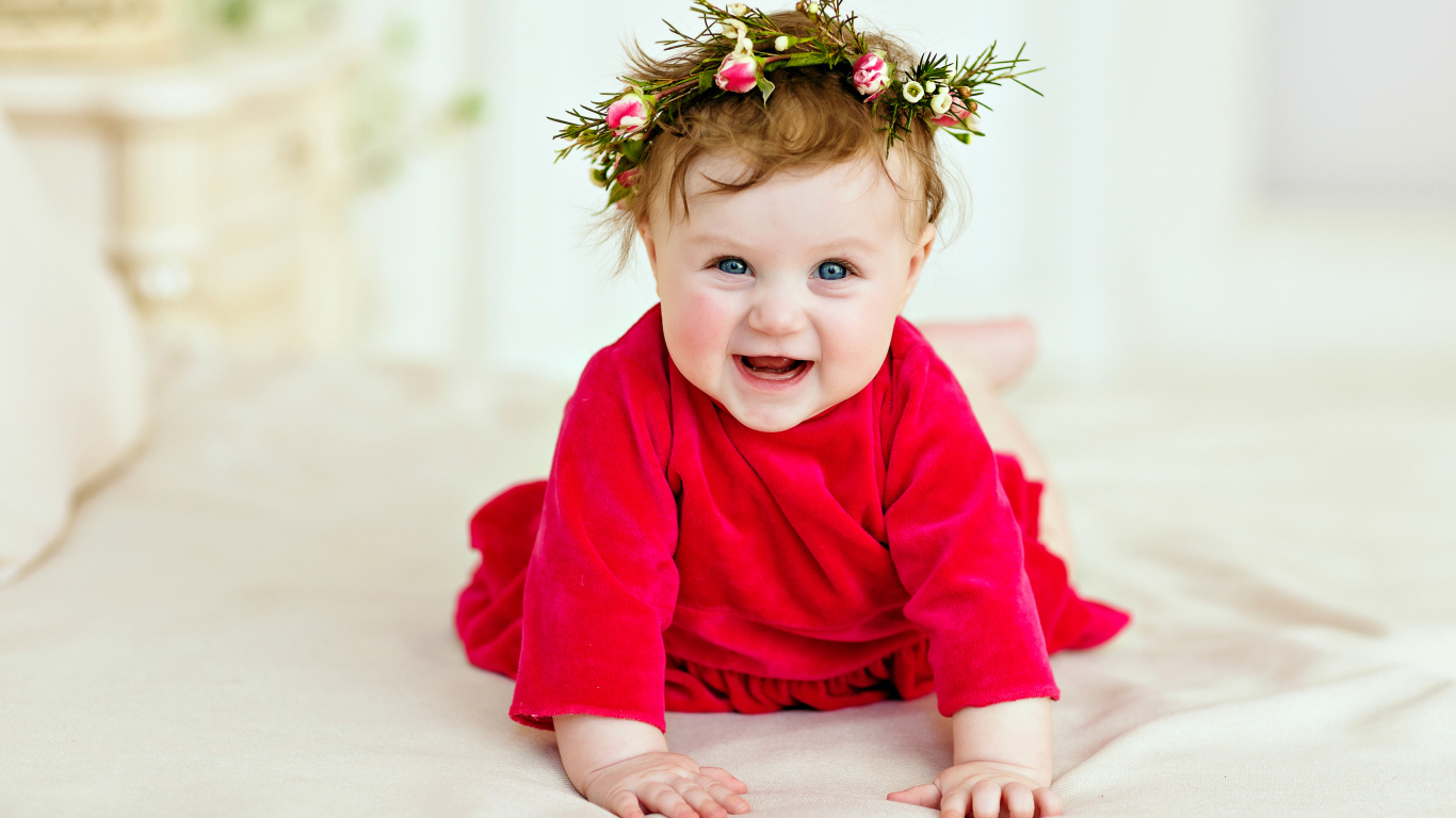 Маленькая улыбающаяся девочка в красном платье с венком на голове