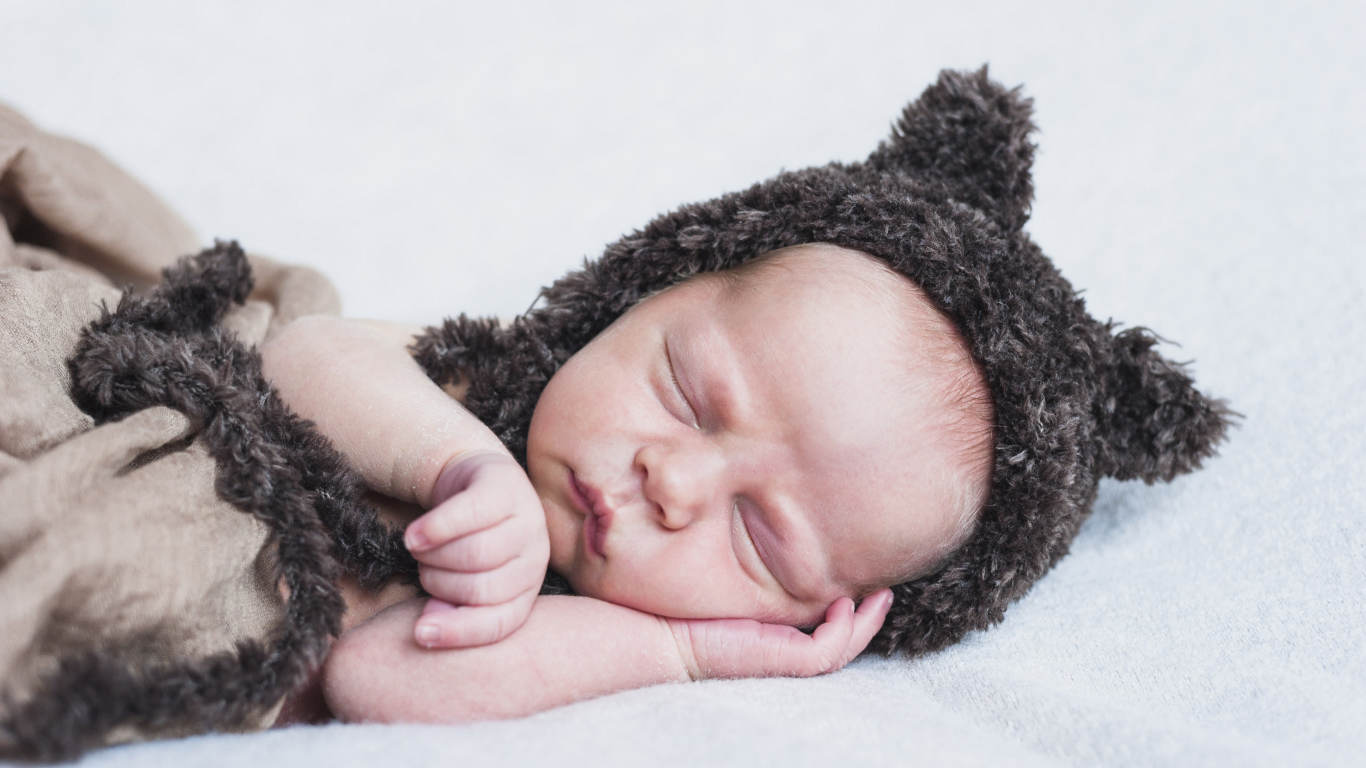 Спящий грудной ребенок в меховой шапке