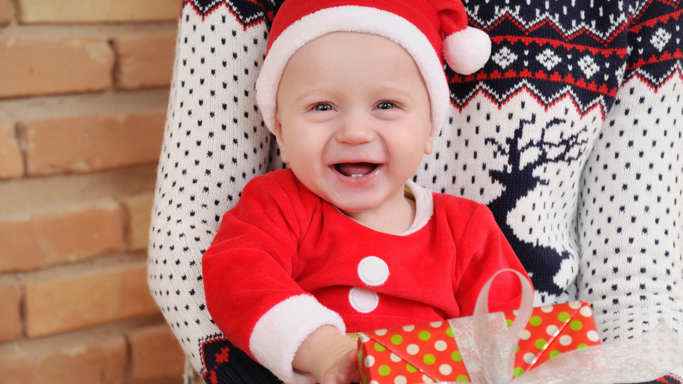 Улыбающийся малыш в костюме с подарком на руках 