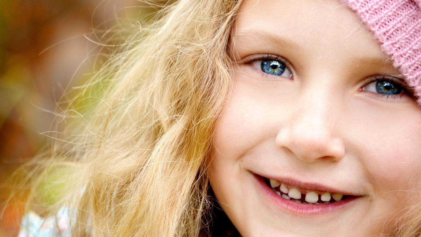 Улыбающаяся светловолосая девочка с голубыми глазами крупным планом