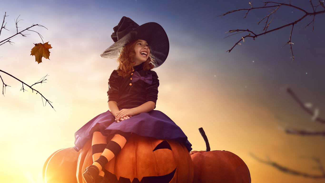 Улыбающаяся девочка сидит на тыкве в костюме на Хэллоуин 