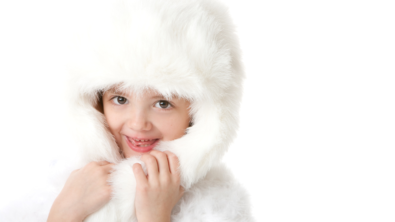 Улыбающаяся маленькая девочка в белой меховой шапке