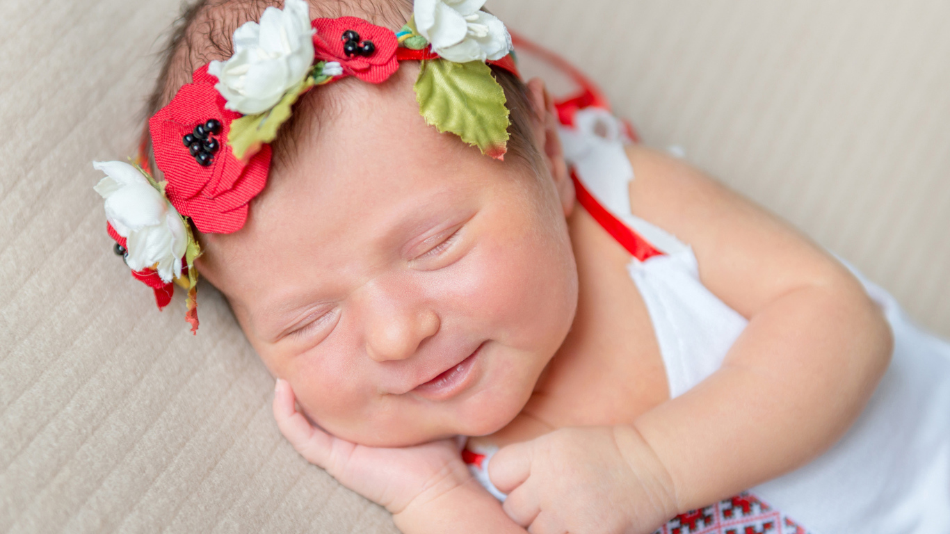Улыбающаяся спящая девочка с венком на голове