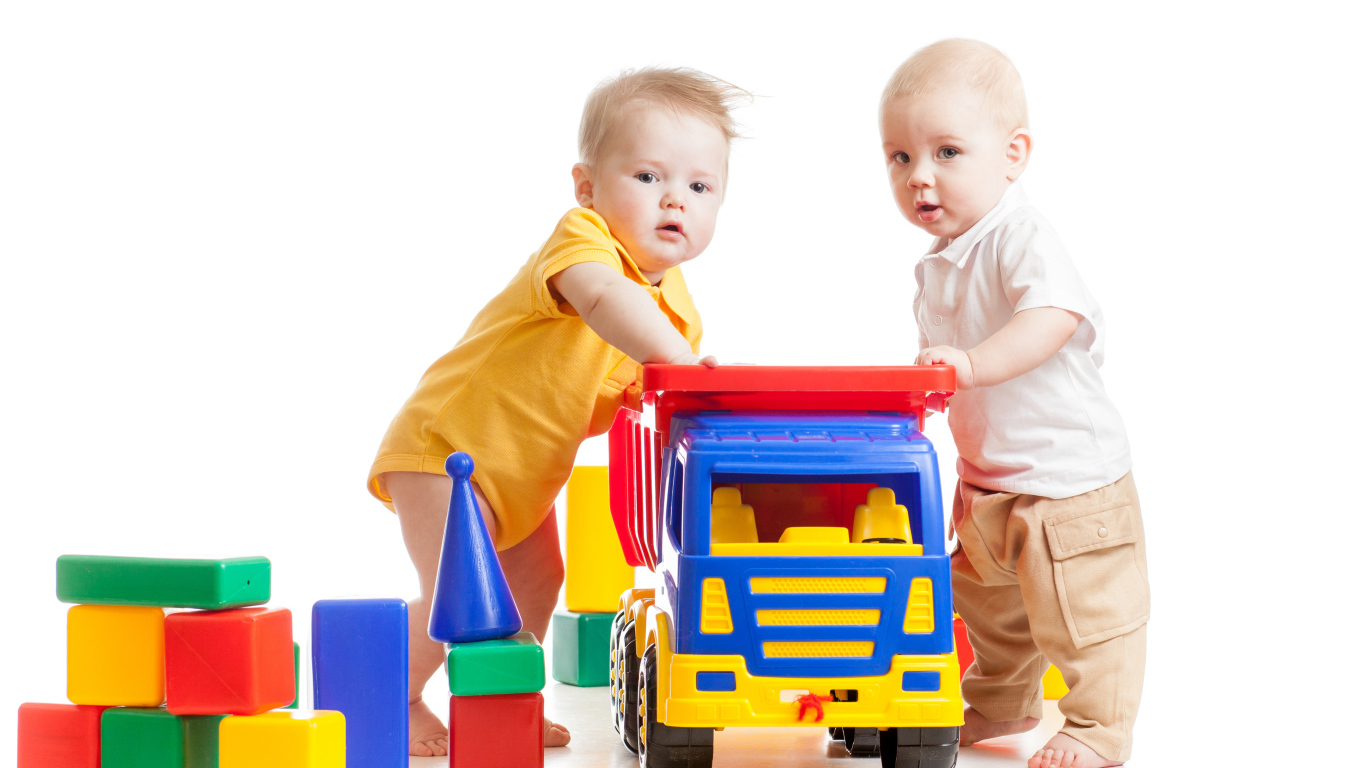 Два маленьких ребенка с игрушками на белом фоне