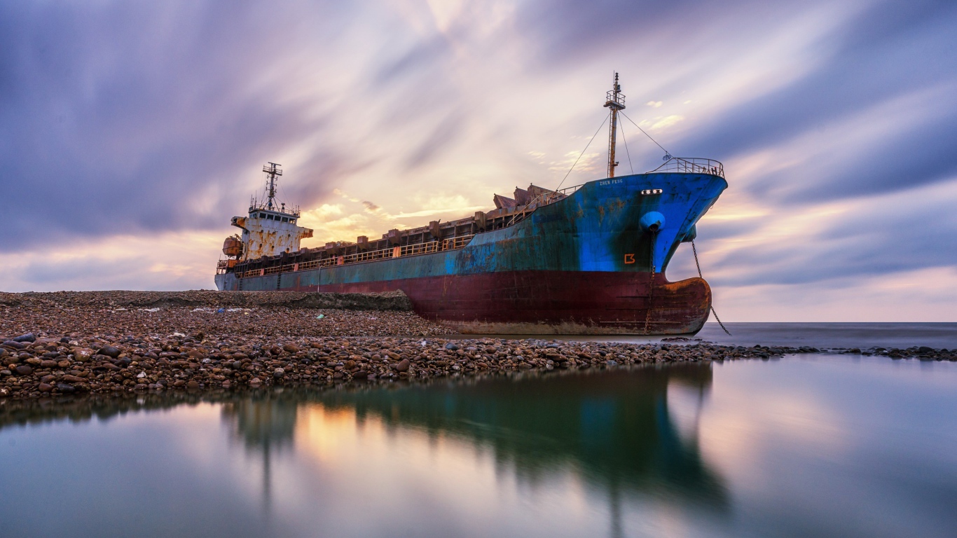 Старый ржавый корабль на берегу под красивым небом