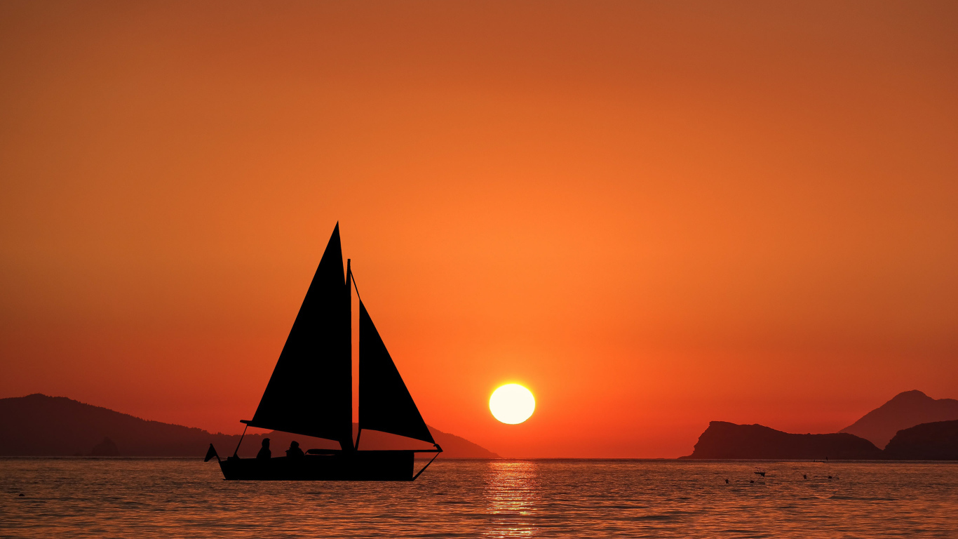 Парусная лодка в море на закате солнца