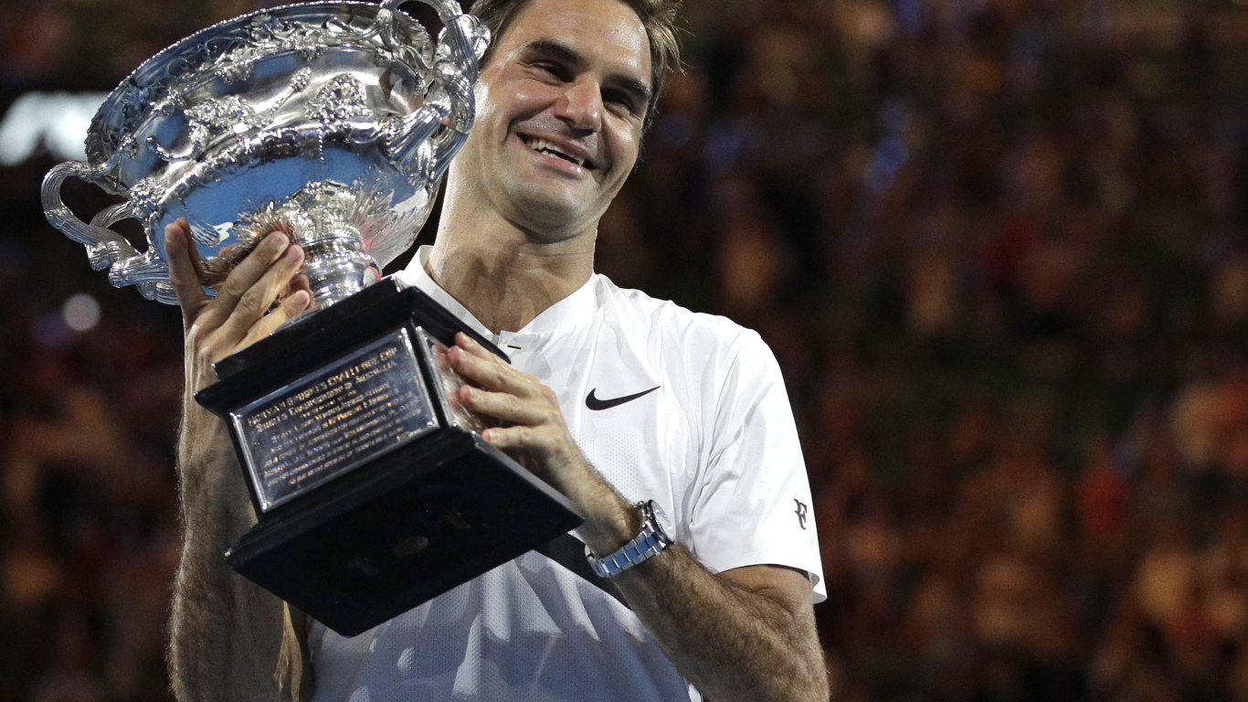 Улыбающийся швейцарский теннисист Роджер Федерер с наградой в руках