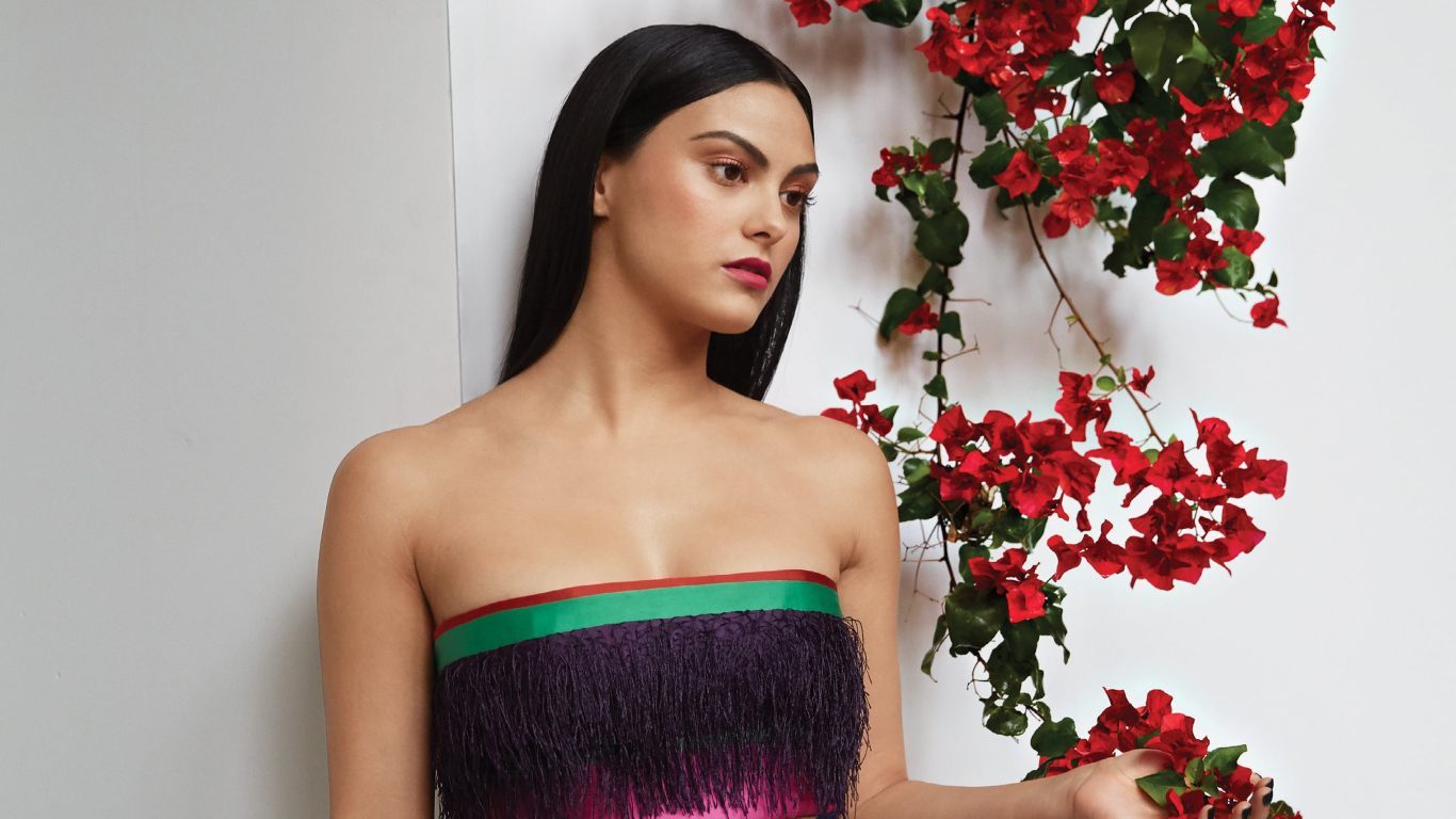 Актриса Камила Мендес стоит у стены с цветами