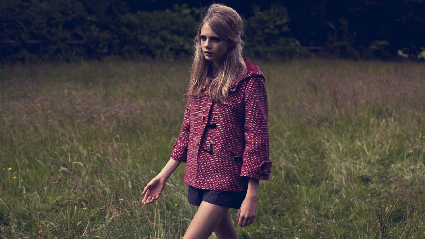 Актриса Кара Делевинь идет по траве в пальто 