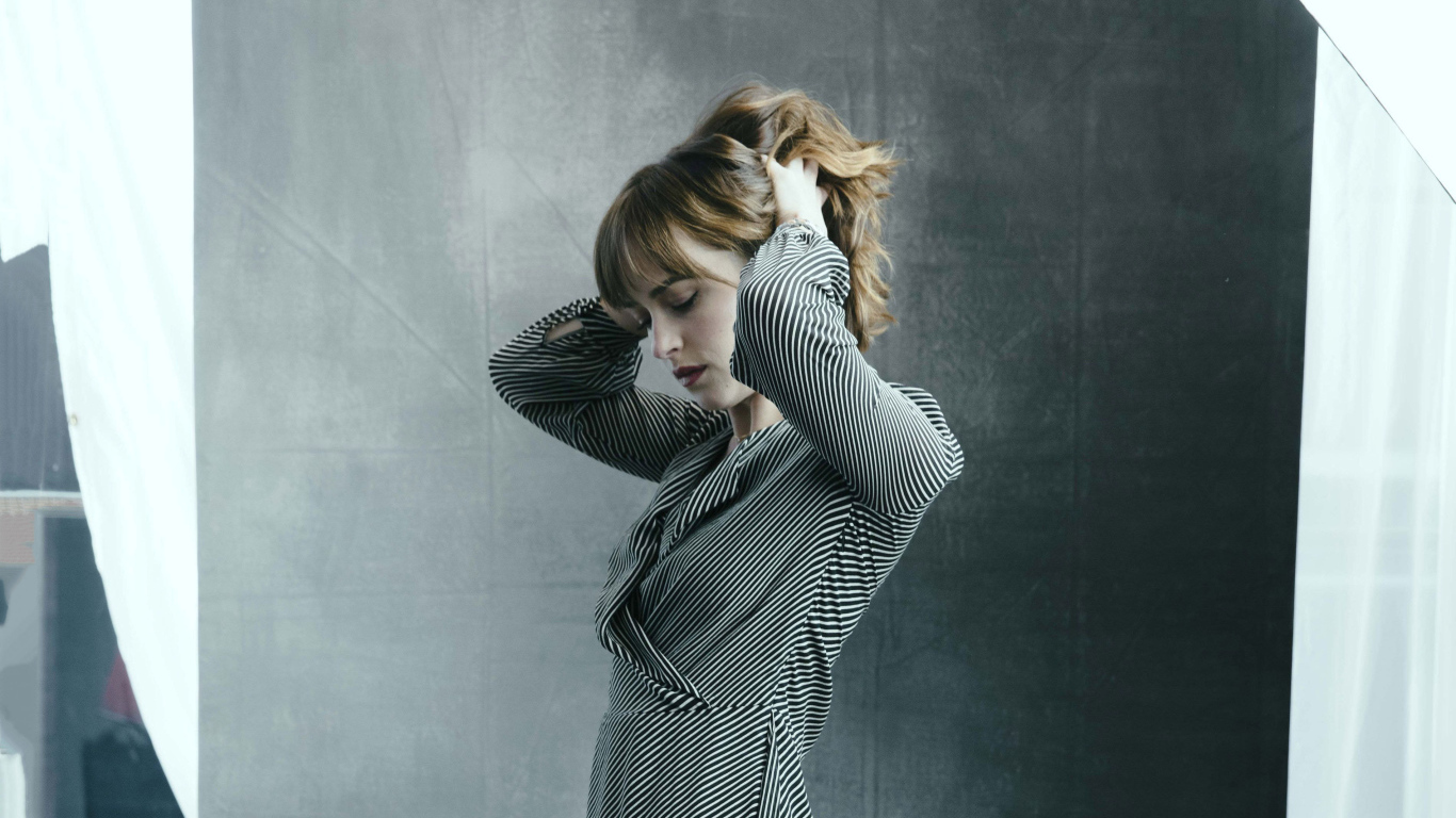 Актриса Дакота Джонсон в платье с руками в волосах