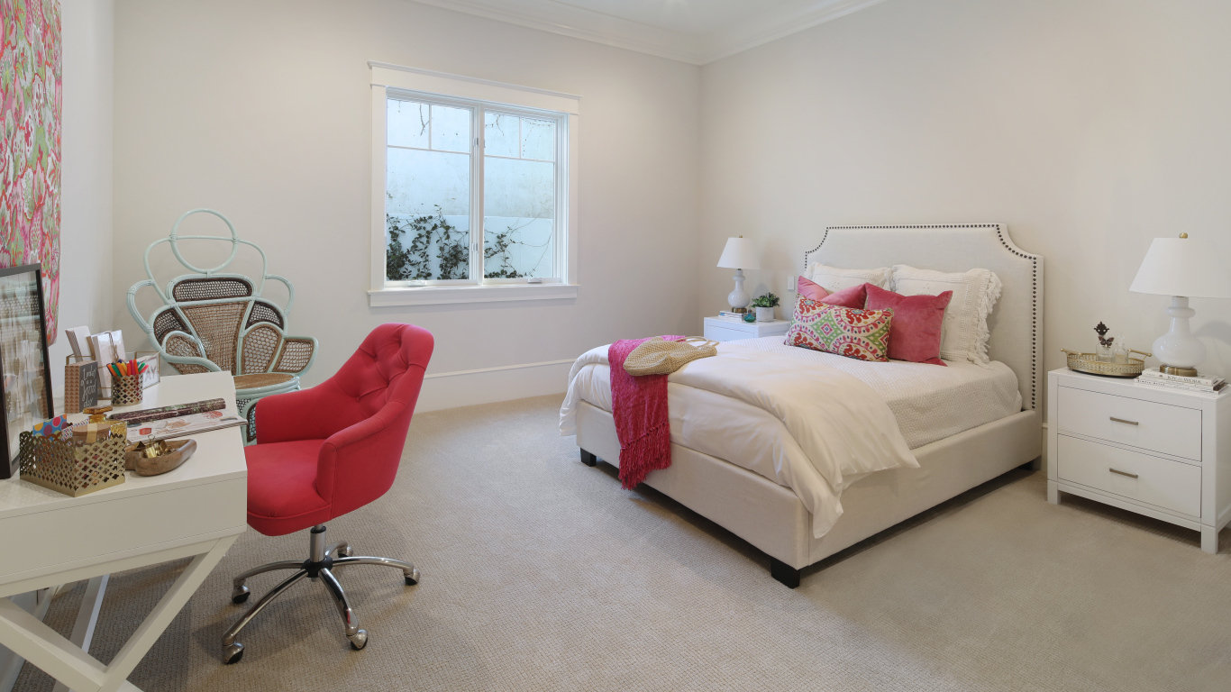 Спальня в светлых тонах с кроватью и столом с красным креслом
