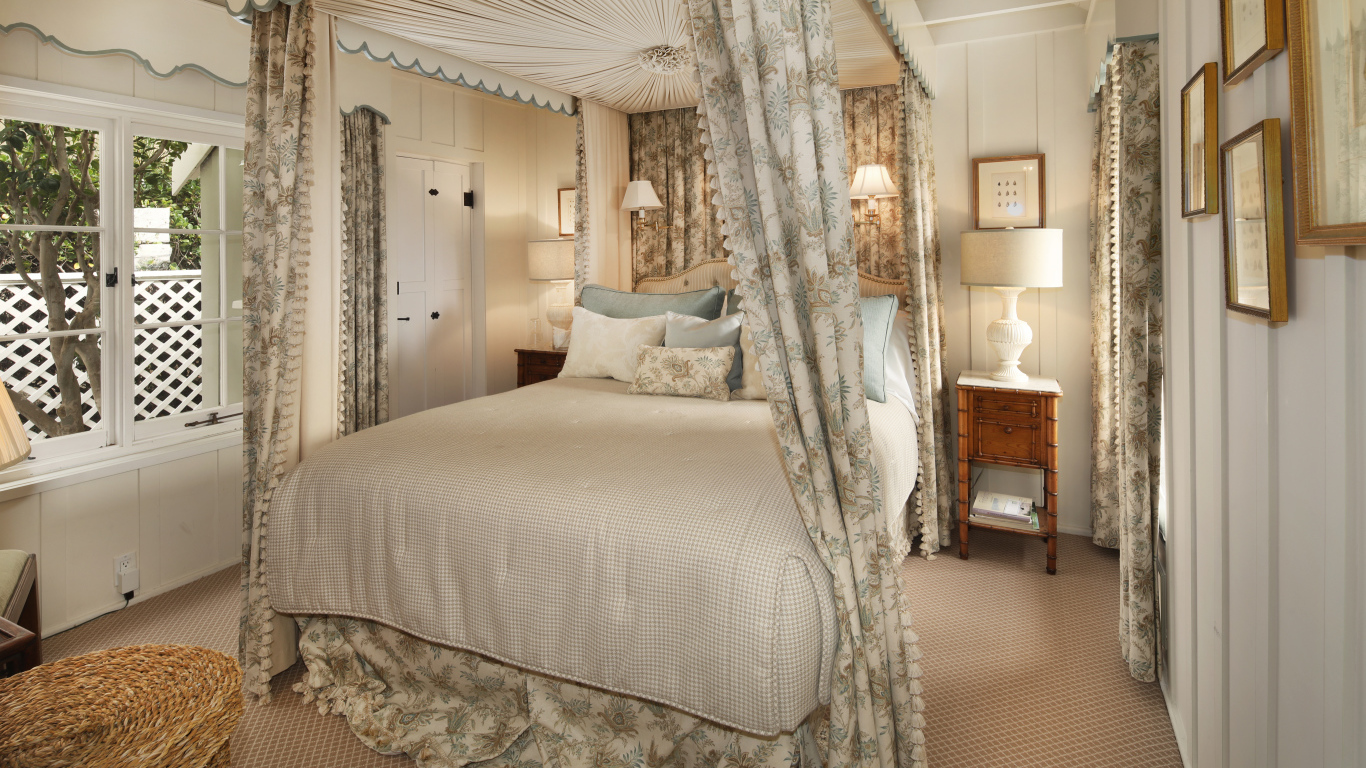 Высокая кровать с занавесками в спальной комнате в пастельных тонах 