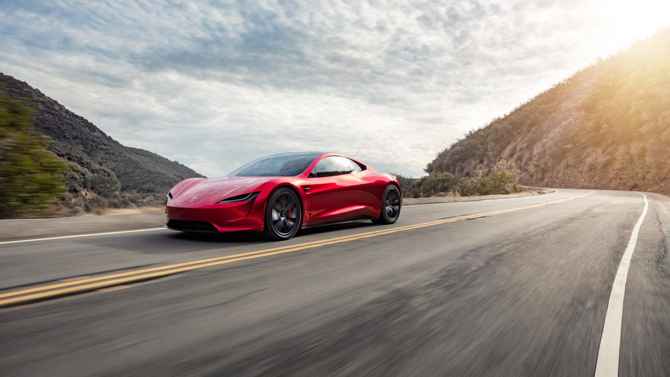 Красный автомобиль Tesla Roadster едет по трассе 