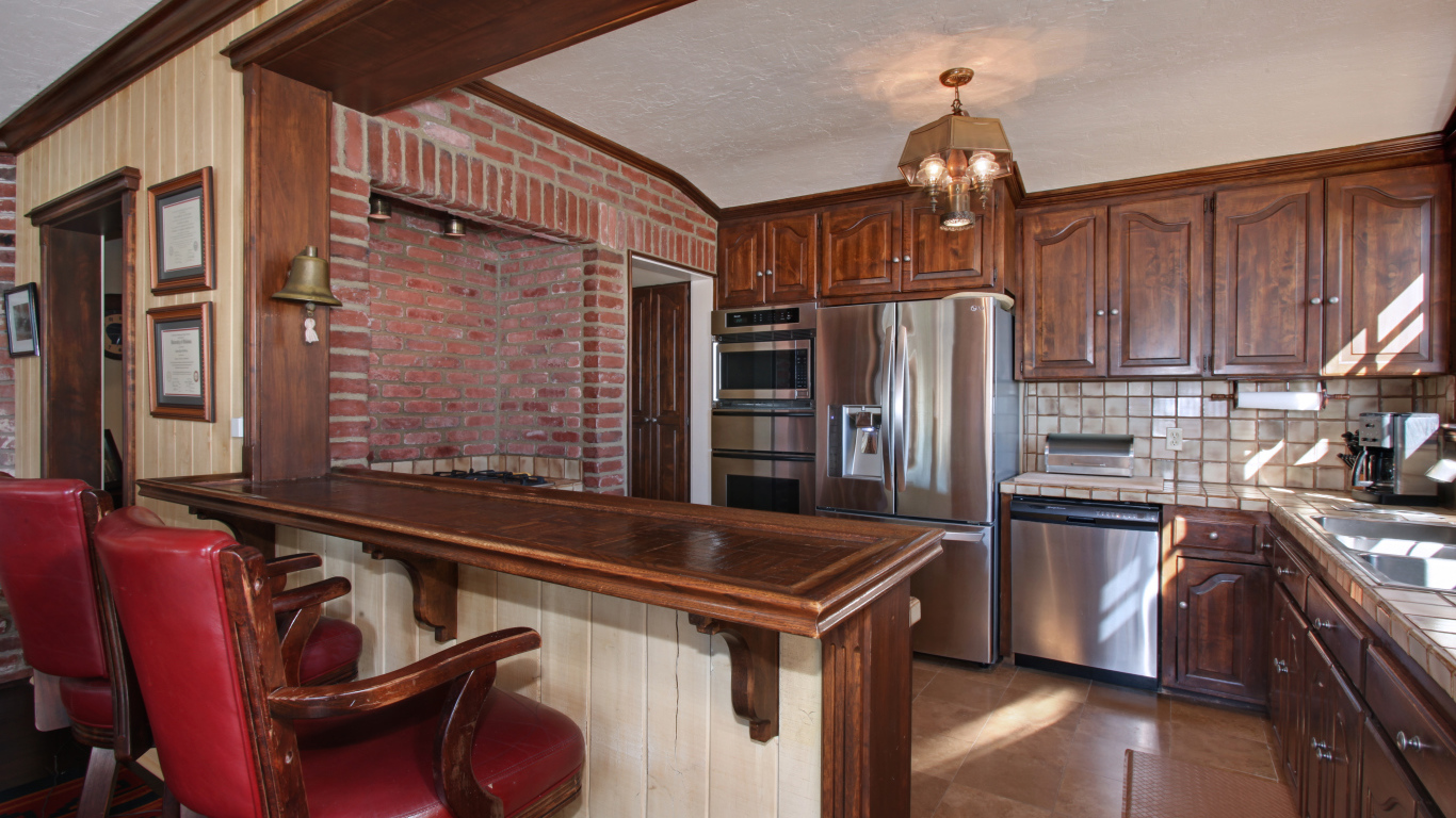 Просторная кухня с деревянной мебелью и кожаными стульями
