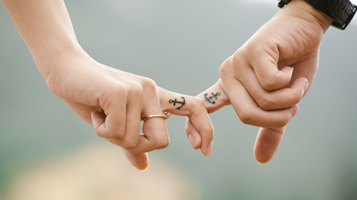 Tattoo with anchor on the fingers of a couple in love