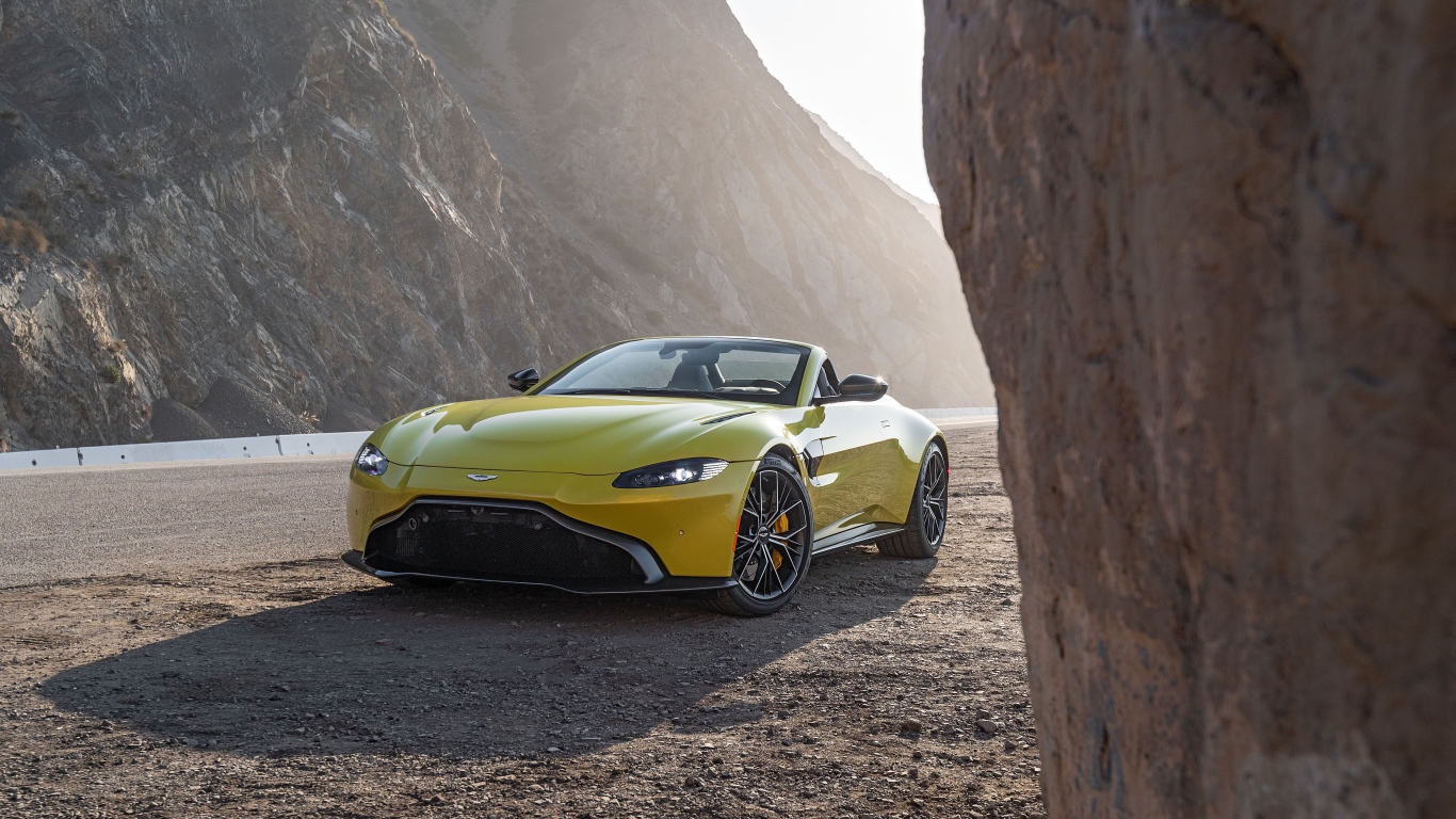 Желтый автомобиль  Aston Martin Vantage Roadster, 2021 года в горах 