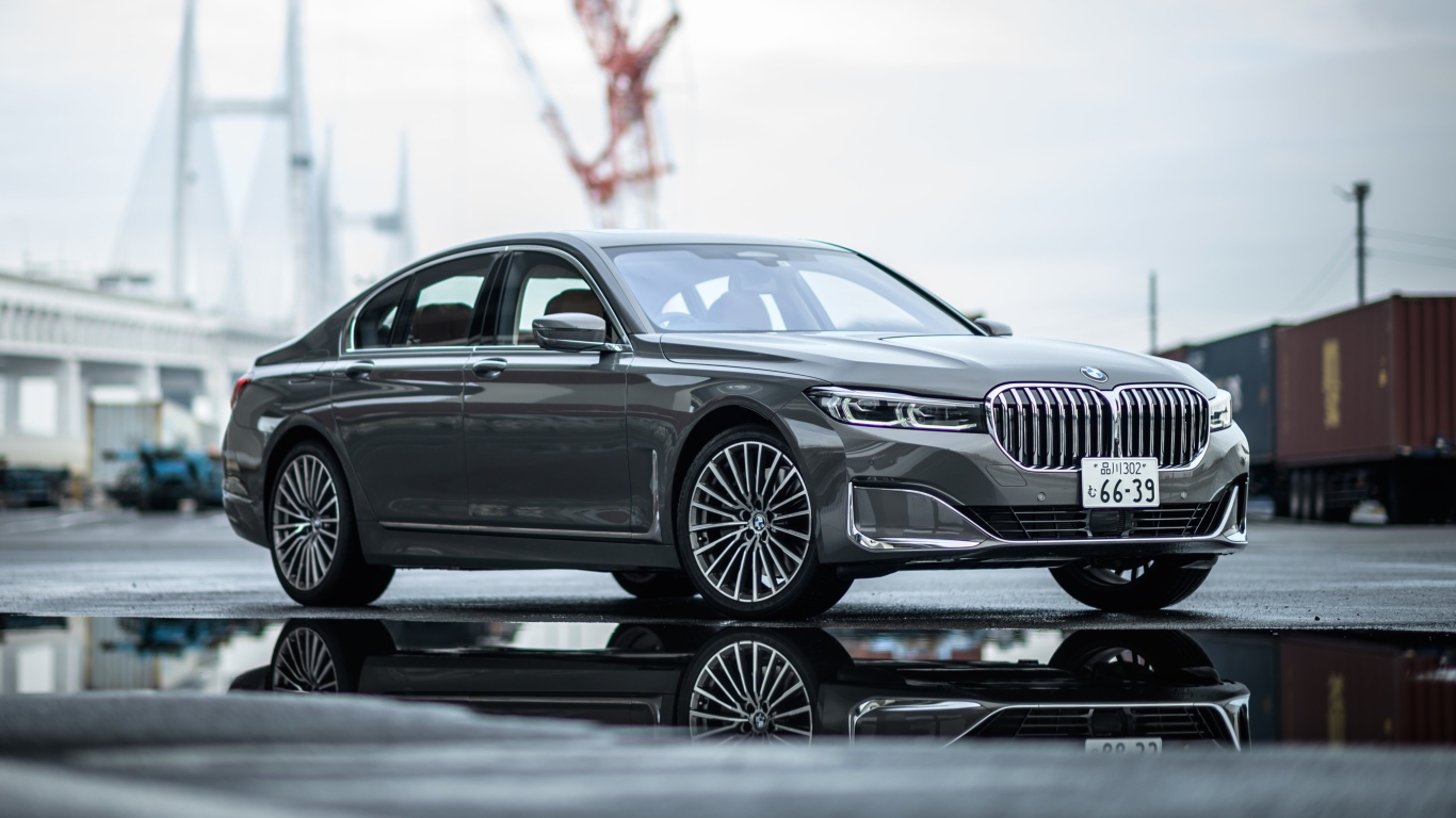 Серебристый автомобиль BMW 745e на мокром асфальте 